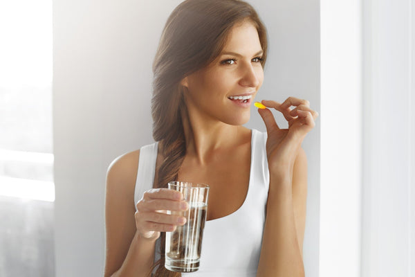 A woman takes a keto supplement pill with a glass of water