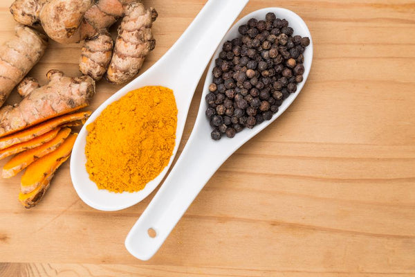 turmeric and black pepper in two different spoons