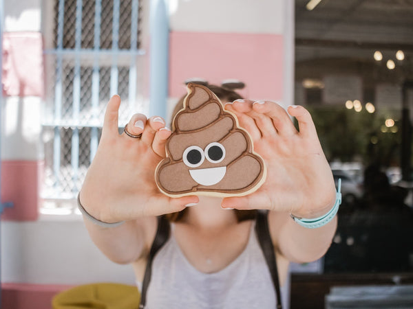 Probiotics for constipation: A woman holds a cookie with the poop emoji on it